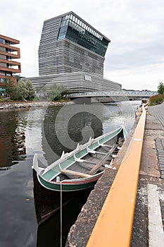 Old boat parked beside the canal in the front of Munch Museum in Oslo, Norway under the cloudy sky
