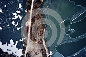 Old boat ship, trapped, frozen in winter ice lake, docked in pier, aerial top down view