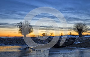 Old boat at sunset on the Danube river in winter