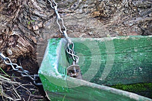 The old boat is tied to a tree trunk by a chain.