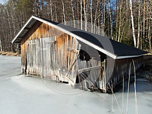 Old boathouse by frozen lake