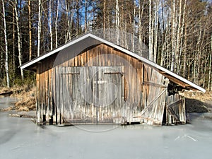 Old boathouse by frozen lake