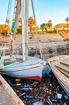 Old boats moored in dirty harbour. Pollution of river, sea, ocean water with waste, plastics garbage.