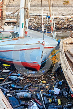 Old boats moored in dirty harbour. Pollution of river, sea, ocean water with waste, plastics garbage