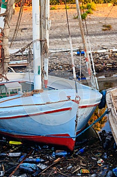 Old boats moored in dirty harbour. Pollution of river, sea, ocean water with waste, plastics garbage