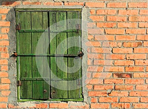 Old bolted wooden window shutters on red brick wall