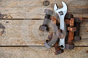 Old bolts with adjustable wrench tools on wooden background photo