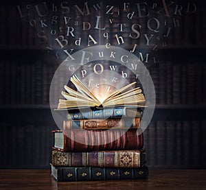 Old book with flying letters and magic light on the background of the bookshelf in the library. Ancient books as a symbol of