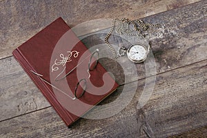 Old book, glasses and pocket watch on a textured table. Old fashioned still life
