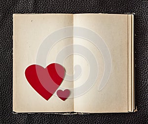 Old book with a heart shape on black leather background