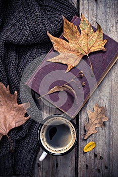 Old book, knitted sweater with autumn leaves and coffee mug