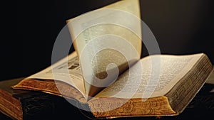 Old book pages detail. Stock footage. Open old book lying on the table with pages turning by wind.