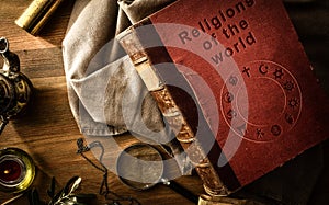 Old book of religions with ancient objects on vintage table