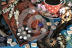 Old book of spells, flowers and runes on witch altar table.