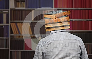 Old book stack and glasses instead the head of man standing opposite library shelfs with many books