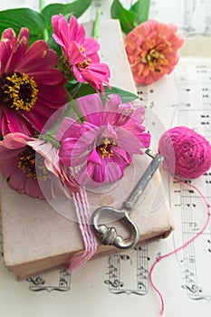 Old book with vintage key and pink flowers zinnia