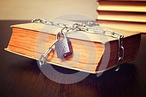 Old book wrapped with chain and locked on padlock on table