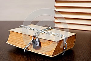 Old book wrapped with chain and locked on padlock on table