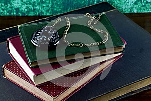 Old Books with Black Pocket Watch on a Wooden Shelf