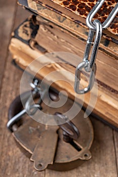 Old books bound by a new shiny chain with an old padlock. Forbidden old works artists on a wooden table