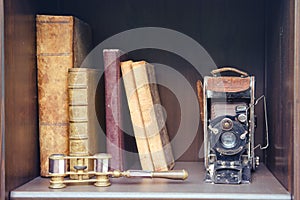 Old books and a camera on a vintage shelf in the closet, close-up