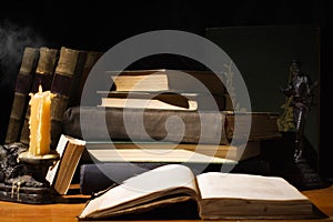 Old books and candles on wooden table