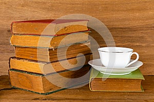 Old books and coffee cup on table