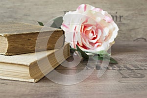 Old books and flower rose on a wooden background. Romantic floral frame background. Picture of a flowers lying on an antique book