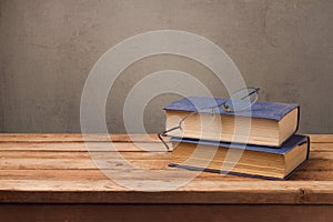 Old books and glasses on wooden table over rustic background. Education