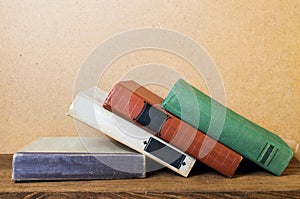 Old books lie on a wooden shelf