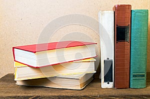 Old books lie on a wooden shelf