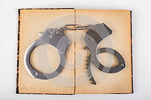 Old books and metal handcuffs. Literature and prison for bad words