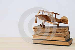 old books next to plane toy on wooden table