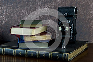 Old Books and Old Folding Camera on a Varnished Wooden Surface