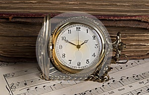 Old books and pocket watch on music background