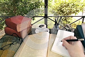 Old books with treatise, glasses and pencil on a wooden table in