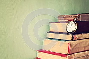 Old books with vintage pocket watch on a wooden table. retro filtered image