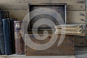 Old books and a wooden box set on a shelf. Old publishing houses