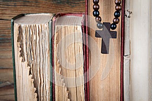 Old books and wooden cross. Religion, prejudice, prohibition and faith concept