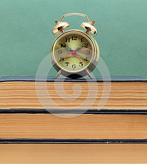 old books on a wooden shelf and alarm clock