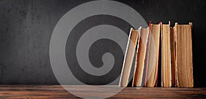 Old books on wooden table and blackboard