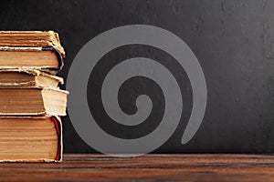 Old books on wooden table and blackboard