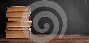 Old books on wooden table and blackboard