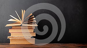 Old books on wooden table and blackboard