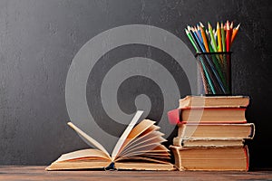 Old books on wooden table and blackboard