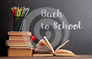 Old books on wooden table and blackboard