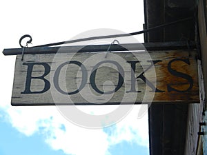 Old Bookstore Sign hanging from wall with blue cloudy sky at the