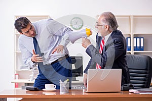 Old boss and young male employee in the office