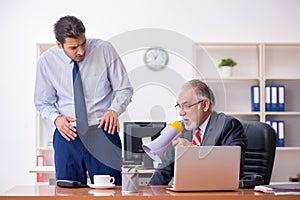 Old boss and young male employee in the office