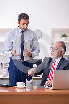 Old boss and young male employee in the office